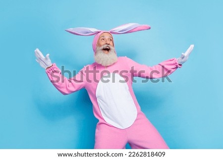 Photo of good mood optimistic man dressed pink rabbit costume look empty space flying palms wings isolated on blue color background