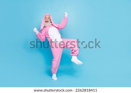 Full length photo of funky lucky retired man wear pink hare pajama rising fists empty space isolated blue color background