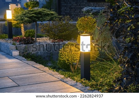 Closeup of Glowing Bollard Lamp in Residential Backyard Garden. Outdoor Lighting and Illumination Theme. Royalty-Free Stock Photo #2262824937