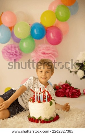 Cute child, preschool boy, celebrating birthday at home with homemade cake with raspberries, mint and candies, balloons and decoration in the room