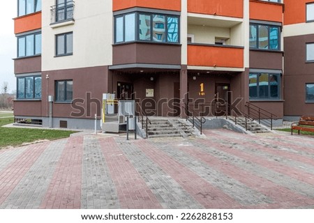 A modern entrance of a residential building equipped with a mechanism for lifting a wheelchair. Lifting ramp with a mechanism for people with disabilities