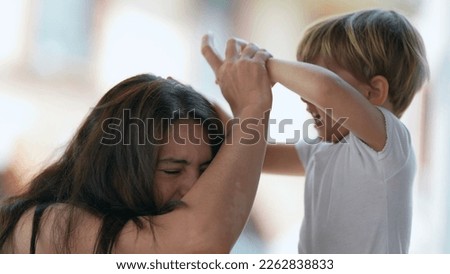 Mischievous child hurting mother. Parenting concept of mom being hit in the head by 2 year old toddler boy. Terrible two concept. Childhood stress concept Royalty-Free Stock Photo #2262838833