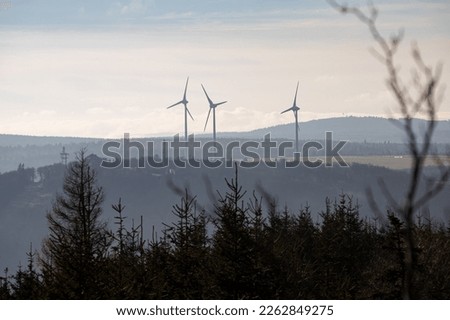 Wind turbines farm in foggy haze, forest landscape