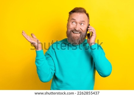 Photo of positive man wear trendy clothes look empty space promoting device shop isolated on yellow color background