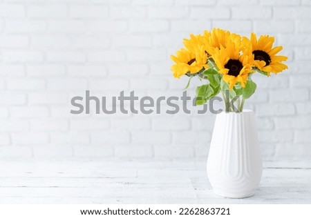 A bouquet of fresh sunflowers in a vase against the background of a white brick wall. copy space for text. Spring or autumn concept, yellow color