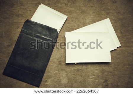 Paper for printing photos from film.Clean white photo paper on the table.A black envelope with photos.