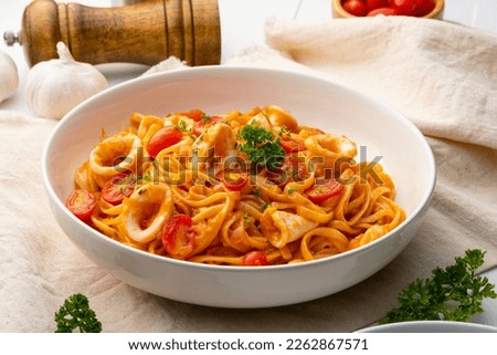 Linguine pasta with squid and cherry tomato in tomato sauce in white plate Royalty-Free Stock Photo #2262867571