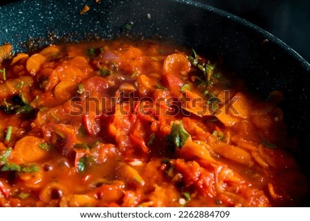 A red tomato sauce cooking steaming in a pan. With carrots, onions, tomatoes and peppers.