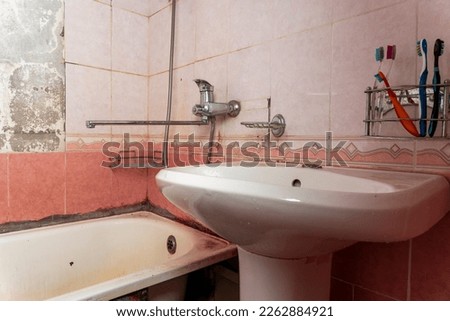 an old dirty shabby bathroom with fallen tiles. an old ruined bathroom Royalty-Free Stock Photo #2262884921