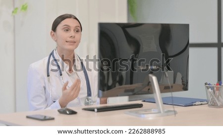 Young Female Doctor Talking on Video Call on Desktop Computer in Clinic