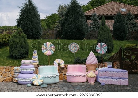 Birthday decor, candies, ice cream, cheesecake on a background of grass near the house.