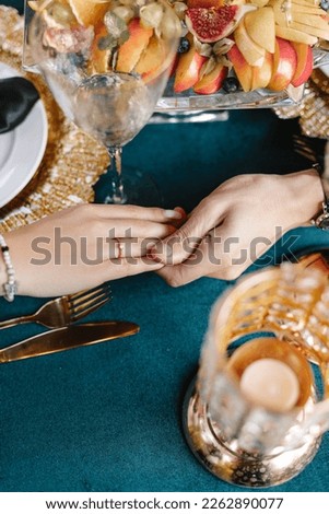 The hands of lovers hold each other on the background of a table decorated for an engagement. She said yes.