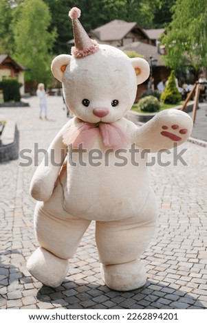 A large figure of a soft toy bear on the street in the park.