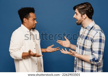 Side view young two friends shocked surprised men 20s wear white casual shirts talk speak together spread hands hear fake news isolated plain dark royal navy blue background. People lifestyle concept Royalty-Free Stock Photo #2262903501