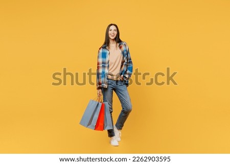 Full body young smiling happy fun cheerful woman wearing casual clothes holding in hand paper package bags after shopping isolated on plain yellow background studio. Black Friday sale buy day concept