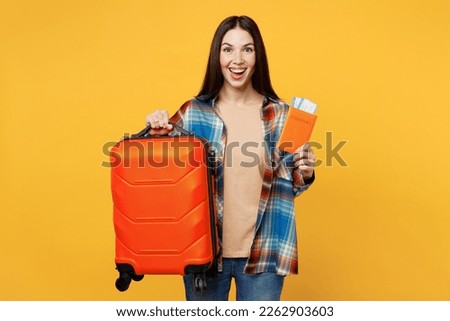 Traveler happy woman wear casual clothes hold valise passport ticket isolated on plain yellow background studio. Tourist travel abroad in free spare time rest getaway. Air flight trip journey concept Royalty-Free Stock Photo #2262903603