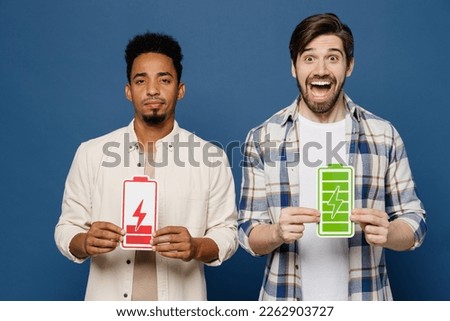 Young two friends sad fun happy tired active cool men 20s wear white casual shirts together hold card sign like battery charge isolated plain dark royal navy blue background. People lifestyle concept Royalty-Free Stock Photo #2262903727
