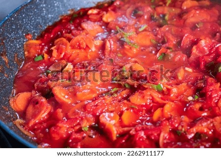 A red tomato sauce cooking steaming in a pan. With carrots, onions, tomatoes and peppers.