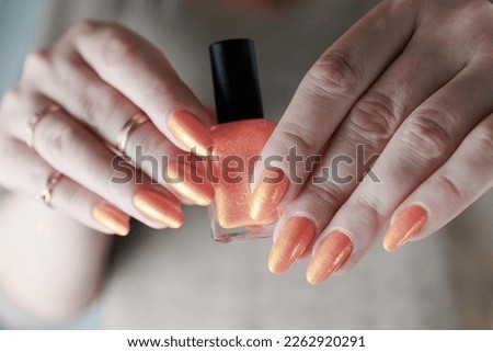 Female beautiful hand with long nails and a neon orange nail polish