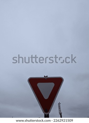 Looming yield sign with overcast sky in the background