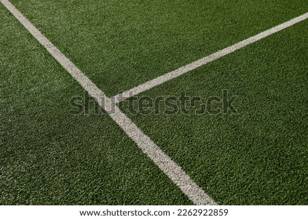 Sports field with green synthetic grass with a white and yellow line. Football, rugby, soccer, baseball concept