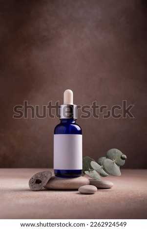 Mockup of skincare cosmetic product. Blue bottle of eco or natural lotion or serum on stone pedestal with eucalyptus branch