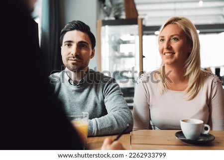 Smiling caucasian couple sitting at the desk across from their financial advisor, carefully listening to what he is saying Royalty-Free Stock Photo #2262933799
