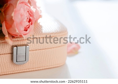 A pink rose lies on a jewelry box, a blurred background with sun highlights. A beautiful banner with a blooming rose flower close-up. Light background with sunlight and space for copy