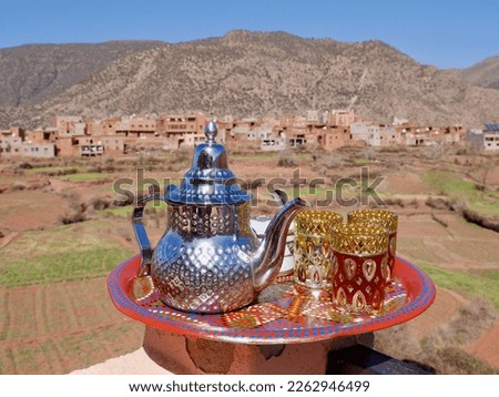 Tea pot with glasses on colorful tray, Ourika valley and High Atlas Mountains in the background. Morocco. High quality photo Royalty-Free Stock Photo #2262946499