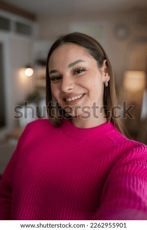 Front view portrait of one caucasian woman young female stand in her apartment at home wear sweater happy confident real people copy space UGC selfie user generated content happy smile Royalty-Free Stock Photo #2262955901