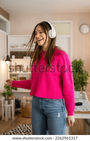 One woman young caucasian female teenager dancing alone at home with headphones on her head having fun while listen to the music happy smile real people copy space