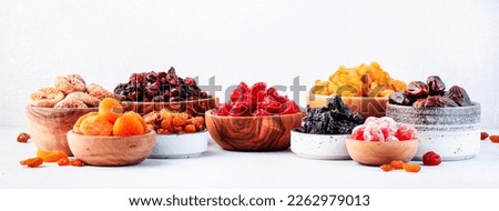 Dried fruits and nuts in bowls set. Dry apricots, figs, raisins, walnuts, almonds and other. Healthy nutritious snacks. White table background, banner