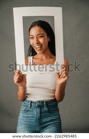Smiling African American female holding frame to frame her face
