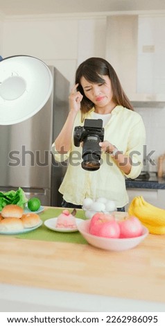 asian female photographer is using digital camera to take pictures in kitchen and she dissatisfied with the work