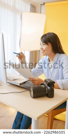 asian female photographer is using color graphic chips to check up colour of pictures in digital camera through laptop computer and she satisfied with the work