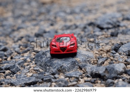 red sports car. a small toy car placed on a cobbled road