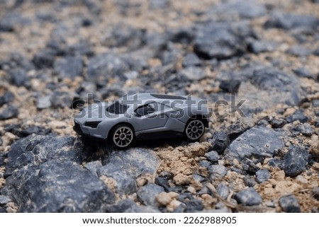 gray sports car. a small toy car placed on a cobbled road