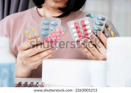 woman choosing medicine and confused about how to use between antibiotics pills and anti-inflammatory drugs   Royalty-Free Stock Photo #2263005213