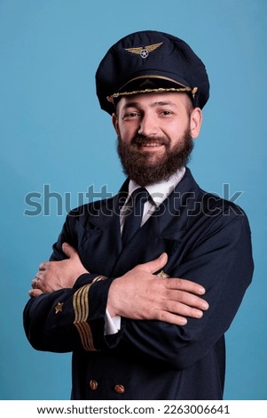 Aircraft aviator standing in professional uniform portrait, confident airplane captain standing, looking at camera, studio medium shot, side view. Civil pilot with badge on jacket