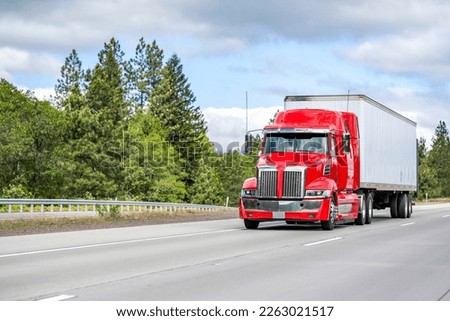 Clean well maintained big rig red semi truck tractor with truck driver rest compartment transporting cargo running on the straight wide highway road with green trees on the side
in Columbia Gorge Royalty-Free Stock Photo #2263021517