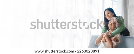 60s asian mother elderly sitting on sofa with young asia female daughter together in living room. hugs with love and encouragement Royalty-Free Stock Photo #2263028891