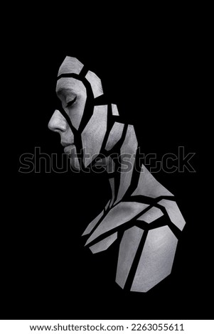 Portrait of person with art creative grey makeup posing in the studio. Shape of gray polygons on beautiful face, shoulders, neck. Pieces of face isolated on dark background. Royalty-Free Stock Photo #2263055611