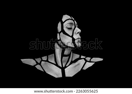 Portrait of person with art creative grey makeup posing in the studio. Shape of gray polygons on beautiful face, shoulders, neck. Pieces of face isolated on dark background.