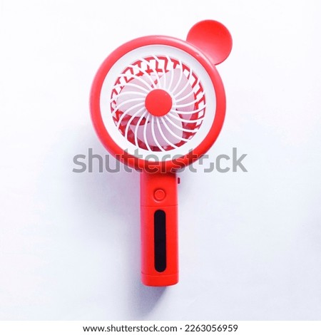The broken red and white portable mini fan isolated on white background. Missing ear. 