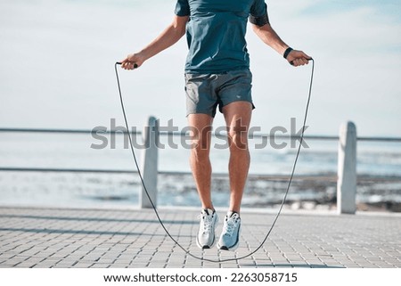Jump rope, fitness and man by a sea promenade with training, sports and exercise equipment. Health, jumping and body wellness of a athlete doing cardio jump for active lifestyle by the ocean Royalty-Free Stock Photo #2263058715