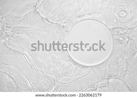 Empty clear white circle podium on transparent calm water texture with splashes and waves in sunlight. Abstract nature background for product presentation. Flat lay cosmetic mockup, copy space.