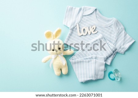Baby shower concept. Top view photo of infant clothes blue shirt pants inscription love knitted bunny toy and pacifier on isolated pastel blue background