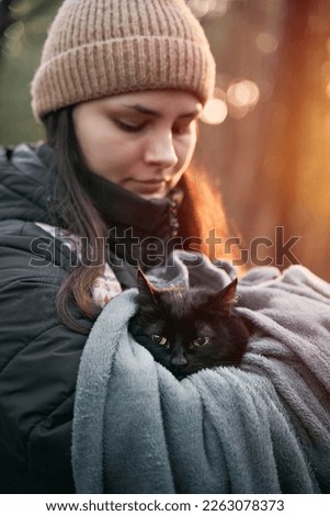 Beautiful young girl holds a black stray cat. close-up of a girl with a kitty in the park outdoor