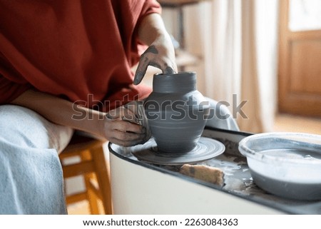 Craftswoman enjoying meditative process of making ceramics, female ceramist shaping clay on pottery wheel while working in studio, selective focus. Craft business and creative hobby concept Royalty-Free Stock Photo #2263084363