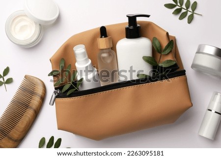 Preparation for spa. Compact toiletry bag with cosmetic products, comb and twigs on white background, top view Royalty-Free Stock Photo #2263095181